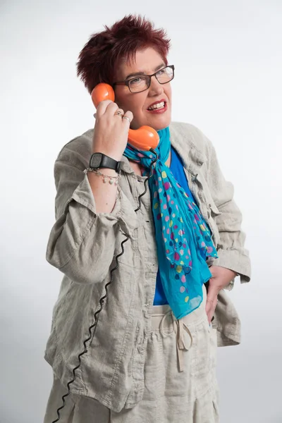 Donna di mezza eta 'che chiama con un telefono arancione vintage. Rosso sho — Foto Stock