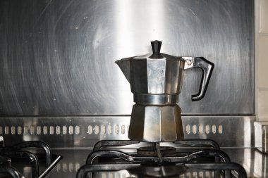 Ocak üzerinde duran klasik metal espresso makinesi.