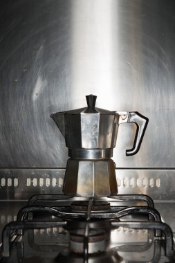 Ocak üzerinde duran klasik metal espresso makinesi.