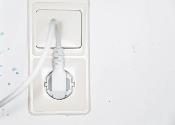 White plug plugged into a white socket on white wall. — Stock Photo, Image