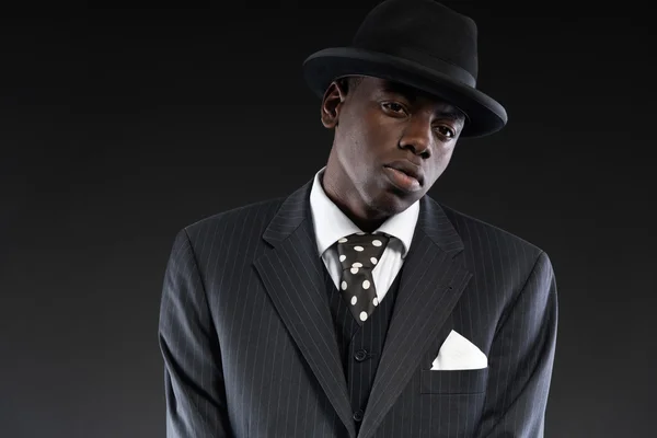 Ρετρό αφρικανικός Αμερικανός γκάνγκστερ φορώντας ριγέ κοστούμι και γραβάτα και — Φωτογραφία Αρχείου