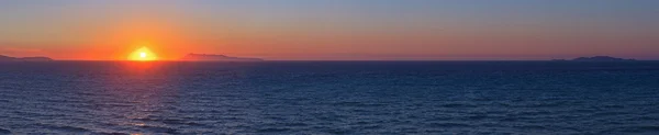 Panorâmica tiro de belo pôr do sol costeiro com algumas ilhas em — Fotografia de Stock