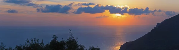 Tiro panorâmico de belo pôr do sol costeiro com céu nublado. Corf. — Fotografia de Stock