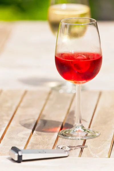 Copa de vino rosa sobre mesa de jardín de madera con llave del hotel. Borroso. —  Fotos de Stock