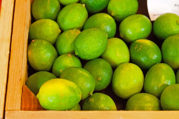 Fresh limes in a wooden crate. — Stock Photo, Image