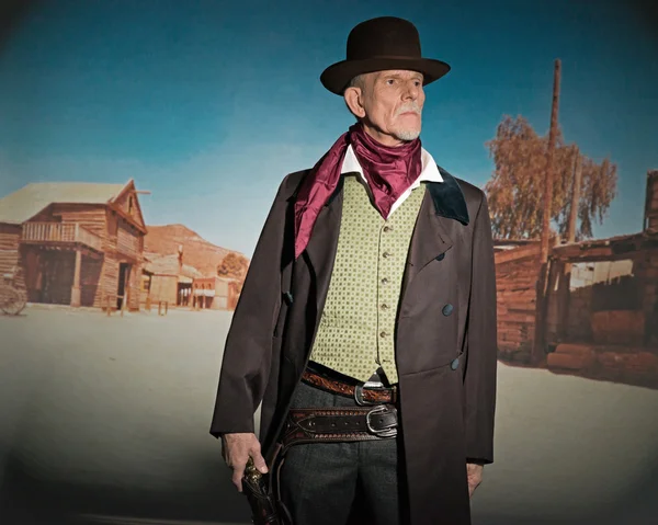 Senior western man wearing a brown hat and coat holding a revolv — Stock Photo, Image