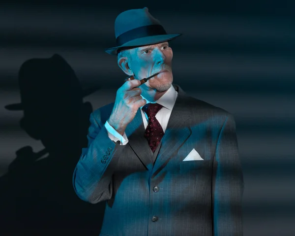 Retro detective man smoking pipe at night in office. Lit by ligh — Stock Photo, Image