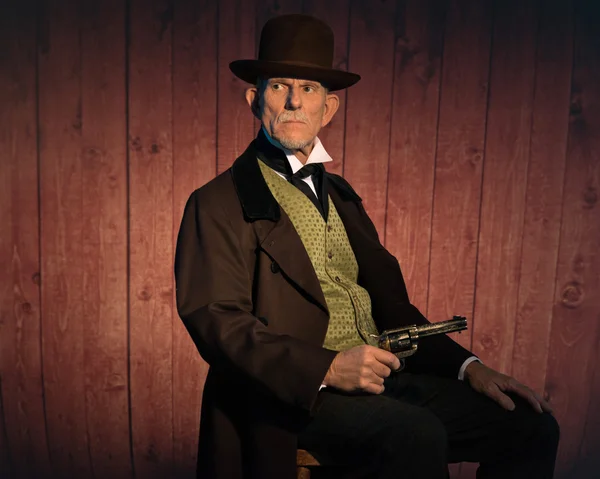 Старший западный человек в коричневой шляпе и пальто с револьвером — стоковое фото