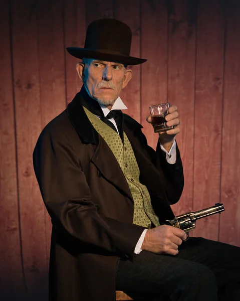 Senior alert western man wearing a brown hat and coat holding a — Stock Photo, Image