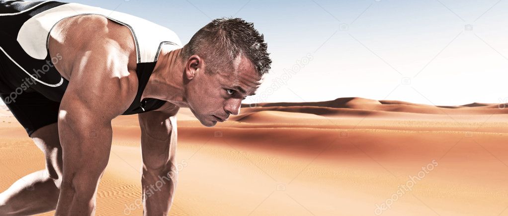 Extreme athlete runner man in starting position outdoor in desert on hot summer day.
