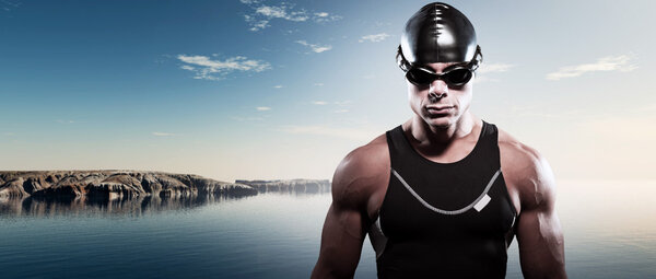 Swimmer triathlon muscled man with cap and glasses outdoor at a