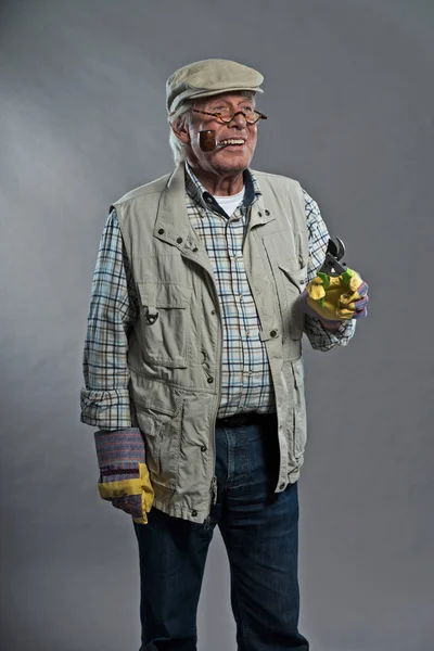 Gardener senior man with hat holding pruning shears. Wearing gla — Stock Photo, Image