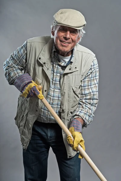 Homme de jardinier principal souriant avec chapeau tenant houe. Studio tourné ag — Photo