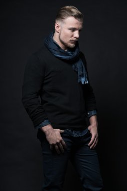 adam kış modası. siyah kazağı ve eşarp takıyor. Sarı saçlı