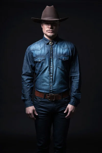 Moderne Mode Cowboy. Er trug einen braunen Hut und ein blaues Jeanshemd. b — Stockfoto