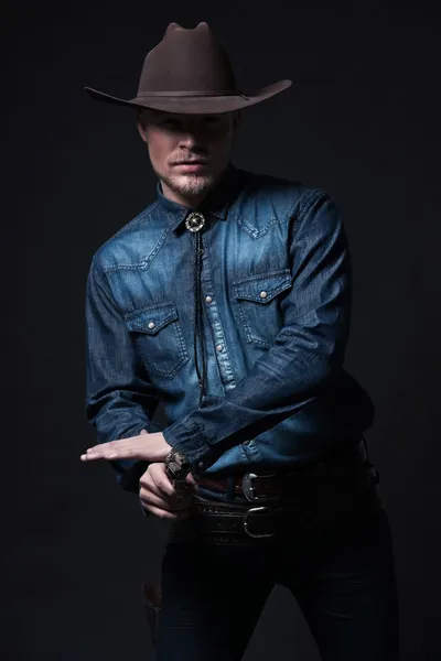 Modern fashion cowboy. Wearing brown hat and blue jeans shirt. P — Stock Photo, Image