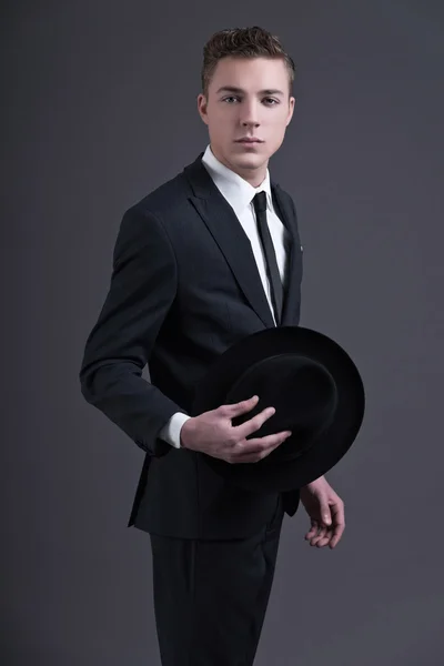 Moda retro años cincuenta joven hombre de negocios con sombrero que lleva su oscuro — Foto de Stock