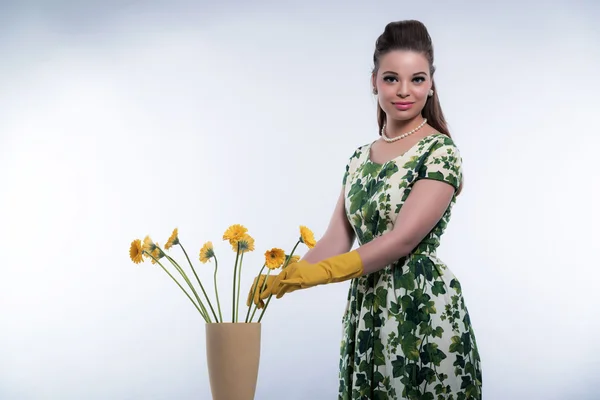 Retro 50s mode huisvrouw dragen van gele rubberen handschoenen. Puttin — Stockfoto