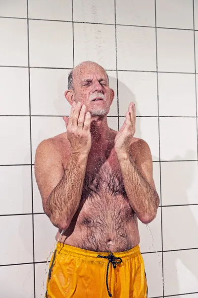 Senior man nemen van een douche in de badkamer. dragen gele zwemmen — Stockfoto