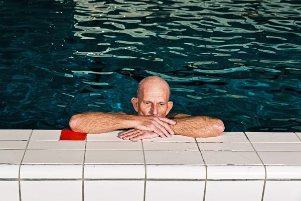 Healthy senior man with beard resting on the edge of an indoor s — Stock Photo, Image