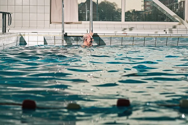 Sano uomo anziano attivo con barba in piscina coperta . — Foto Stock