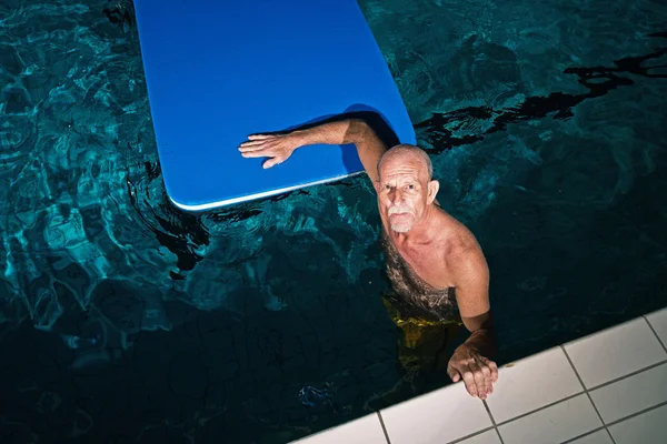Gezonde actieve senior man met baard in binnenzwembad pla — Stockfoto