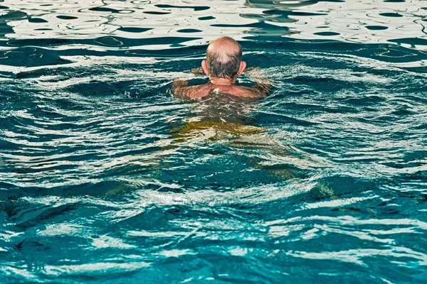 Homme âgé en bonne santé avec barbe dans la piscine intérieure. Vue arrière — Photo