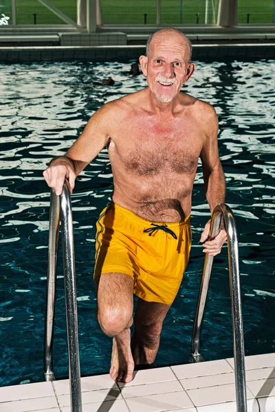 Senior man walking out of swimming pool. Wearing yellow swimming — Stock Photo, Image