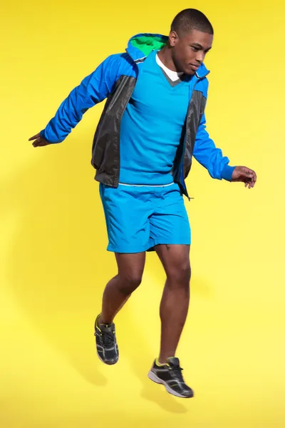 Jumping athletic black man in sportswear fashion. Runner with ho — Stock Photo, Image