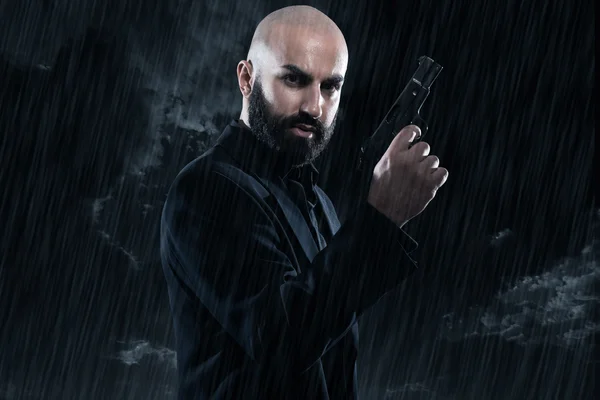 Dangerous bald gangster man with beard holding gun. Wearing blac — Stock Photo, Image