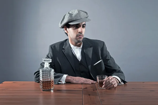 Mafia fashion man wearing grey striped suit with cap. Sitting at — Stock Photo, Image