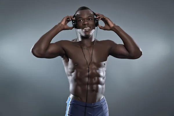 Black african american muscled fitness man with headphones liste — Stock Photo, Image