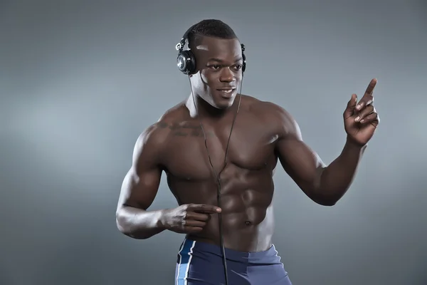 Negro africano americano musculado fitness homem com fones de ouvido liste — Fotografia de Stock