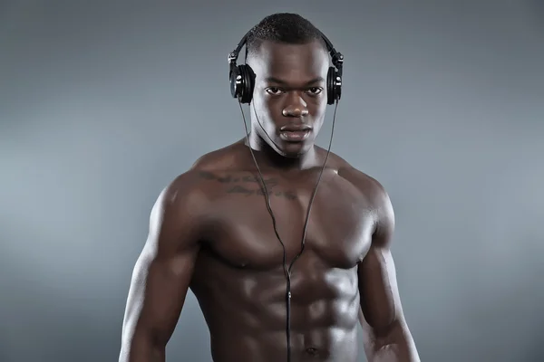 Negro africano americano musculado fitness homem com fones de ouvido liste — Fotografia de Stock