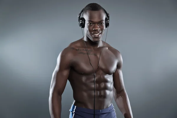 Black african american muscled fitness man with headphones liste — Stock Photo, Image