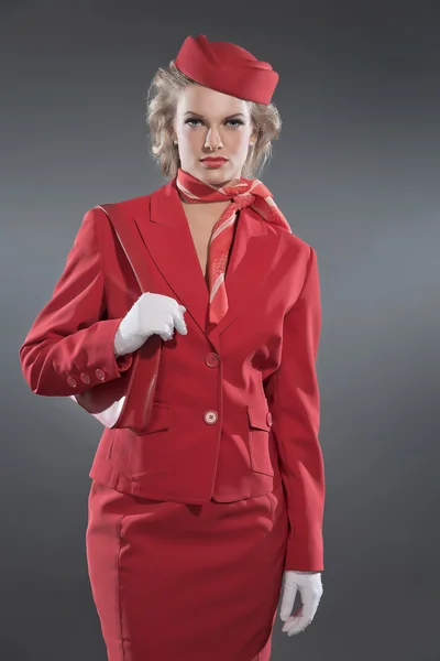 Ρετρό ξανθιά αεροσυνοδός που φοράει κόκκινο κοστούμι και ΚΑΠ. Studio που γυρίστηκε ag — Φωτογραφία Αρχείου