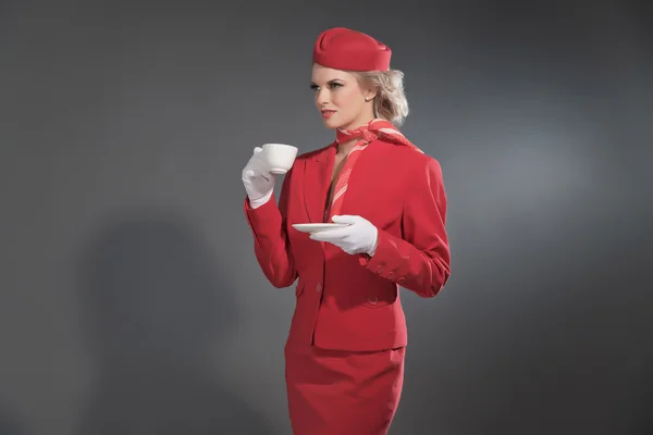 Retro-blonde Stewardess im roten Anzug mit Mütze. Haltebecher o — Stockfoto