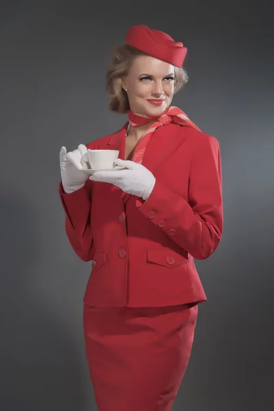 Uśmiechnięty retro blondynka stewardessa noszenie czerwony garnitur z WPR. HOLDi — Zdjęcie stockowe