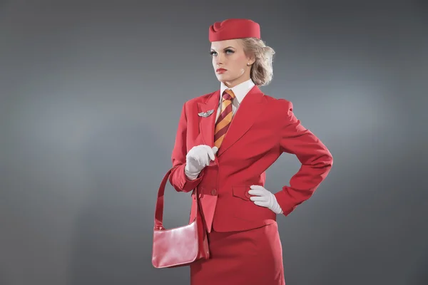 Retro blonde stewardess wearing red suit with striped tie and ca — Stock Photo, Image