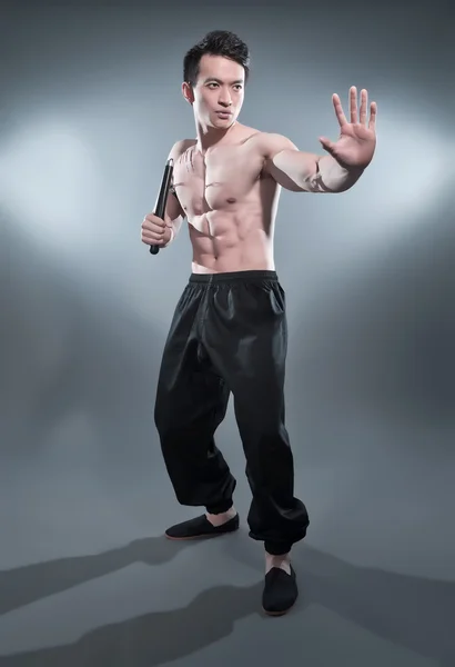 Muscled asiático kung fu homem em ação pose com nunchucks. Sangue s — Fotografia de Stock