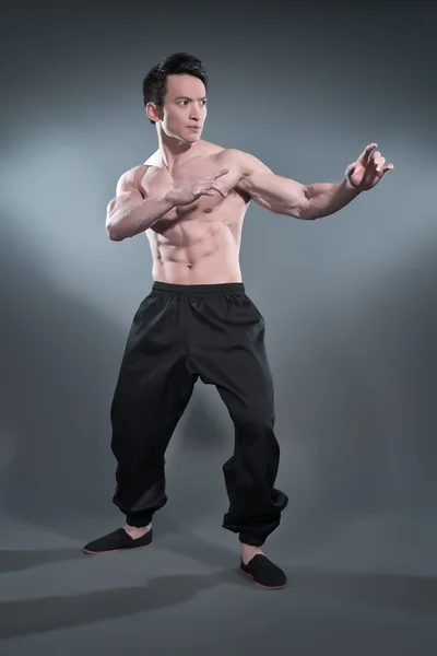 Muscled asiatiska kung fu mannen i aktion pose. svarta byxor. s — Stockfoto