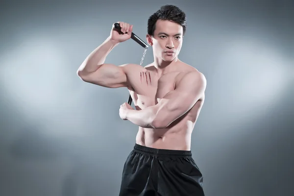 Muscled asian kung fu man in action pose with nunchucks. Blood s — Stock Photo, Image