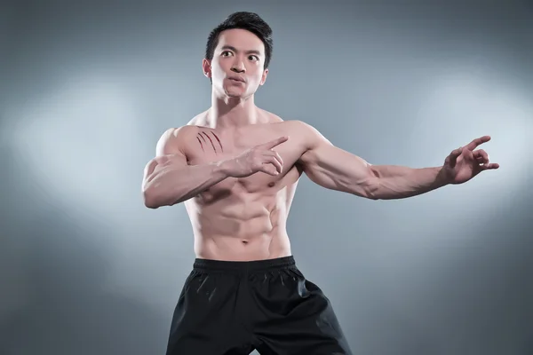 Muskulöser asiatischer Kung-Fu-Mann in Action-Pose. Blutstreifen an seinem c — Stockfoto