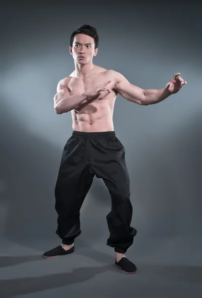 Muscled asiatiska kung fu mannen i aktion pose. svarta byxor. s — Stockfoto