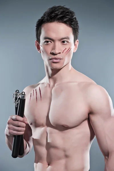Musculado asiático kung fu homem com nunchucks. Riscos de sangue no seu — Fotografia de Stock