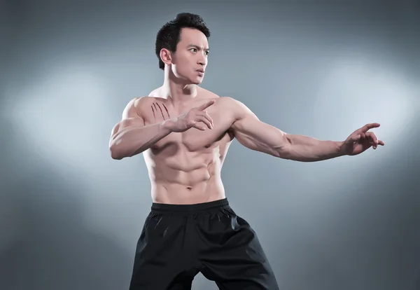 Muscled asian kung fu man in action pose. Blood stripes on his c — Stock Photo, Image