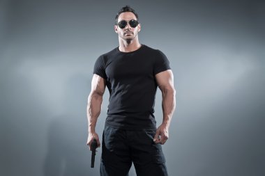 aksiyon kahramanı kaslı adam elinde bir silah. siyah t-shirt zekâ giyiyor