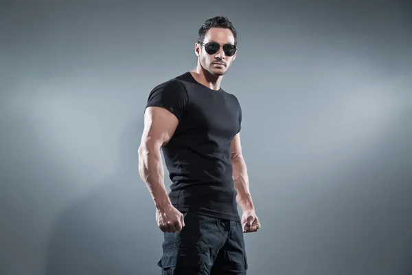 Combat muscled action hero man wearing black t-shirt with pants — Stock Photo, Image