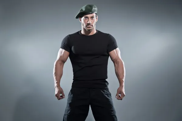 Comandante musculoso héroe de acción hombre vistiendo camiseta negra y pantalón —  Fotos de Stock