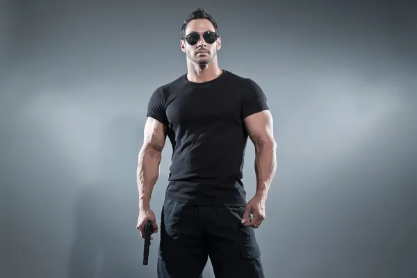 Un héros d'action musclé tenant une arme. Porter t-shirt noir esprit — Photo